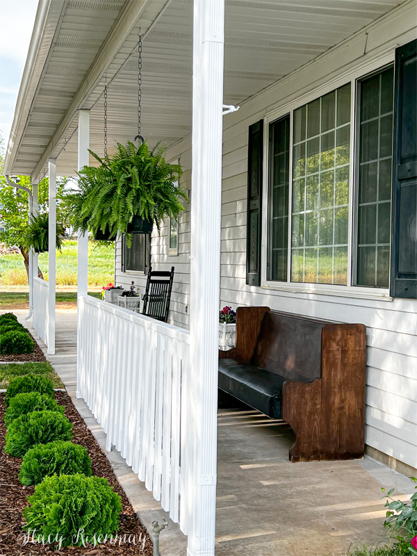 front porch with ferns and pew bench