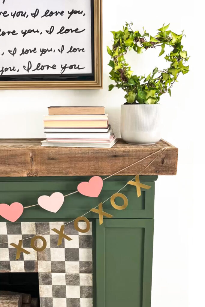 fireplace mantel decorated for Valentines day with a houseplant and heart shaped trellis
