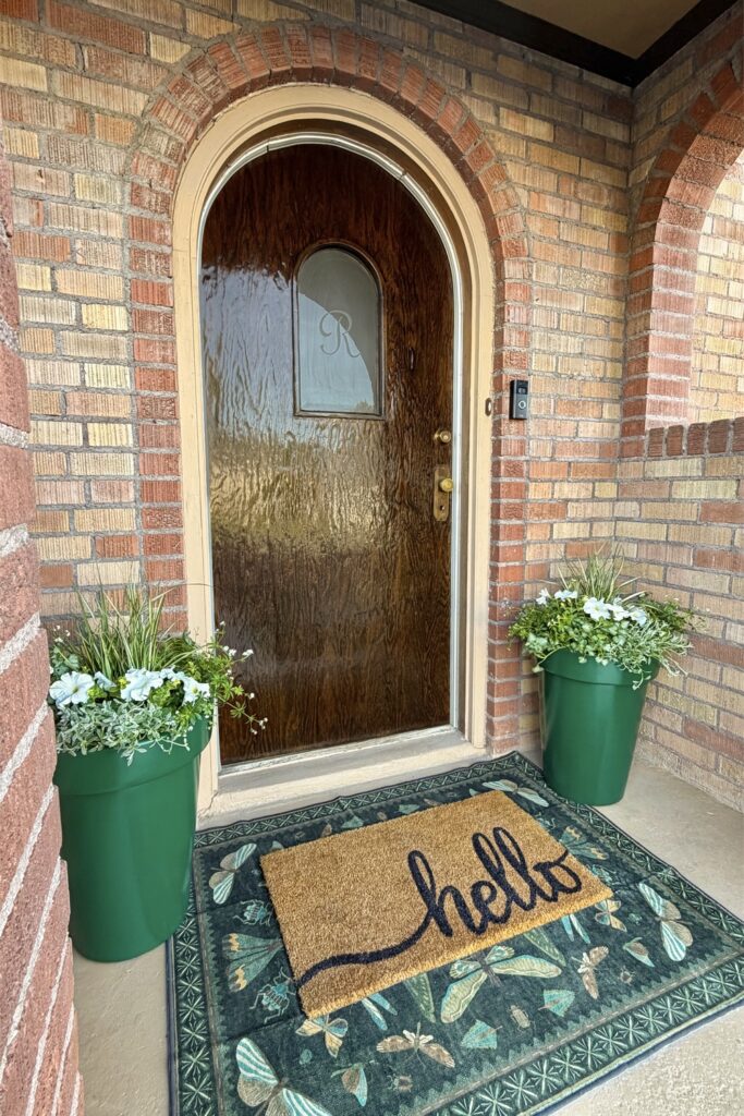 front porch with rounded front door and green planters